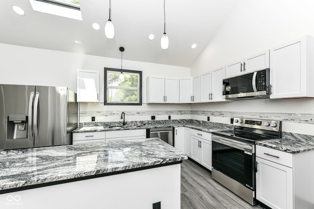 kitchen featuring a sink, tasteful backsplash, stainless steel appliances, white cabinets, and lofted ceiling