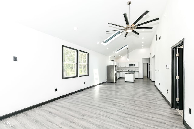 unfurnished living room with ceiling fan, light wood-style floors, high vaulted ceiling, and a skylight