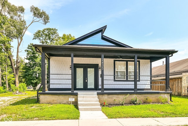 bungalow-style house with a porch, french doors, and a front yard