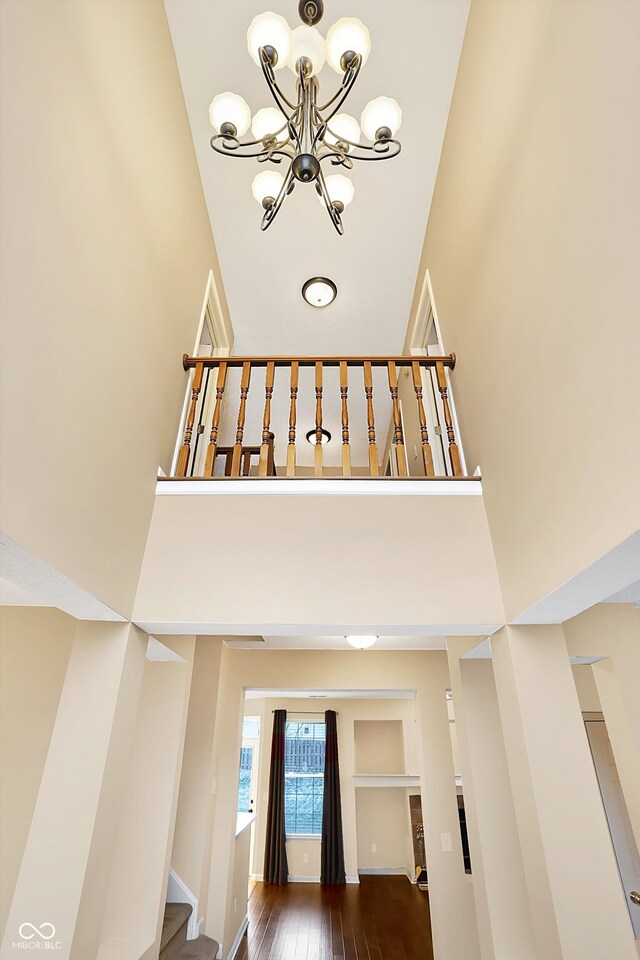 stairs featuring a notable chandelier, wood-type flooring, and a high ceiling