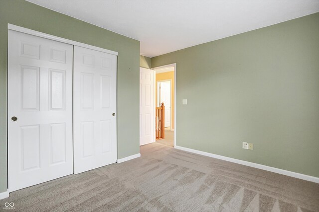 unfurnished bedroom featuring light colored carpet and a closet