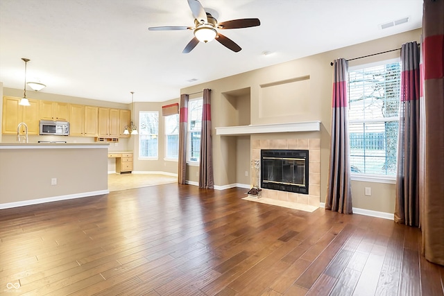 unfurnished living room featuring dark hardwood / wood-style floors, plenty of natural light, and a tiled fireplace