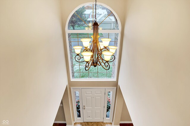 foyer featuring plenty of natural light, a chandelier, and a high ceiling