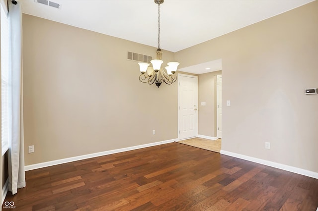 unfurnished room with dark wood-type flooring and a chandelier