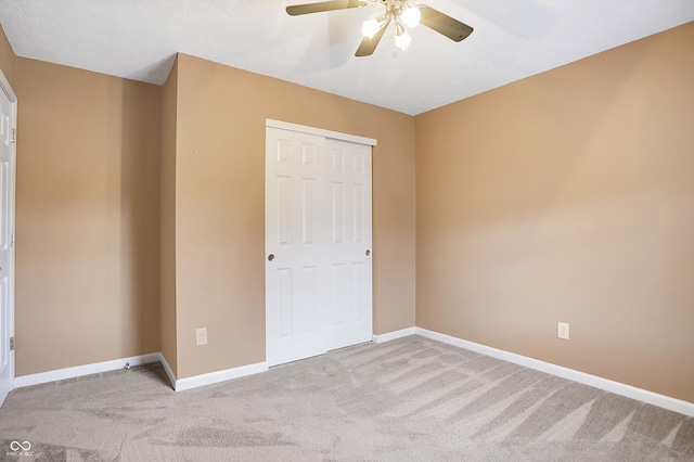 unfurnished bedroom featuring ceiling fan, light colored carpet, and a closet