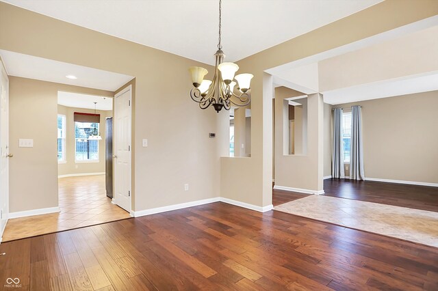 unfurnished dining area featuring a notable chandelier and hardwood / wood-style flooring