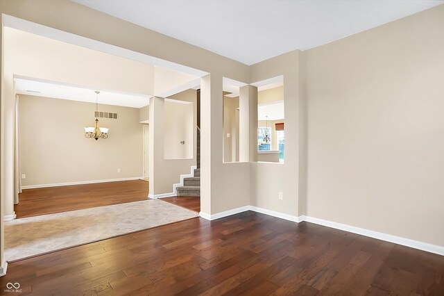 empty room featuring dark wood-type flooring and an inviting chandelier