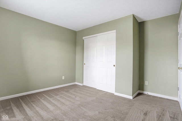 unfurnished bedroom with light colored carpet and a closet