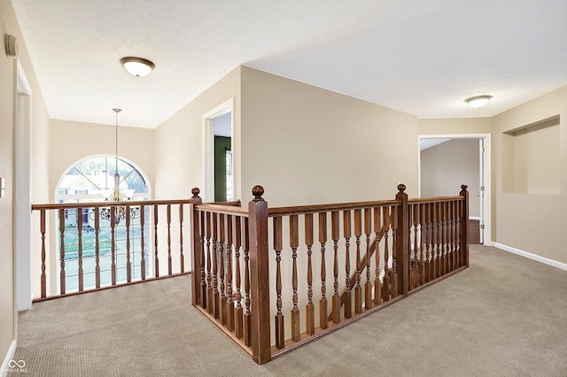 corridor featuring a chandelier and light colored carpet