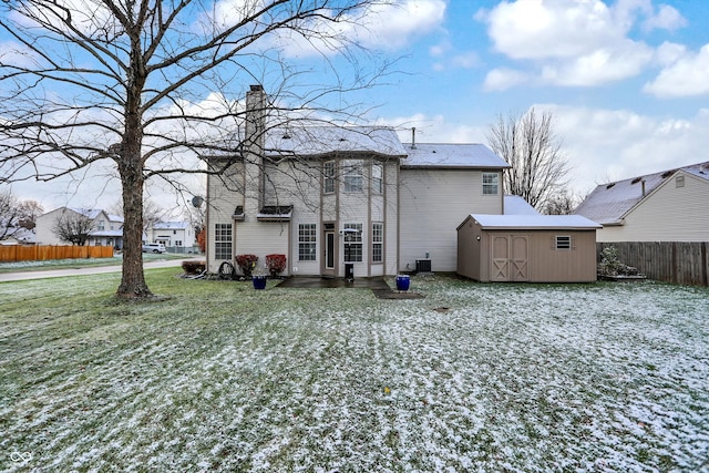 rear view of property with a lawn, central AC unit, and a shed