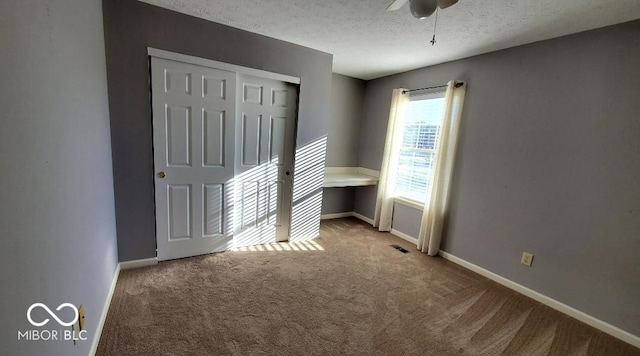 carpeted spare room with a textured ceiling and ceiling fan