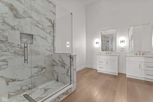 full bathroom featuring a marble finish shower, a sink, baseboards, and wood finished floors