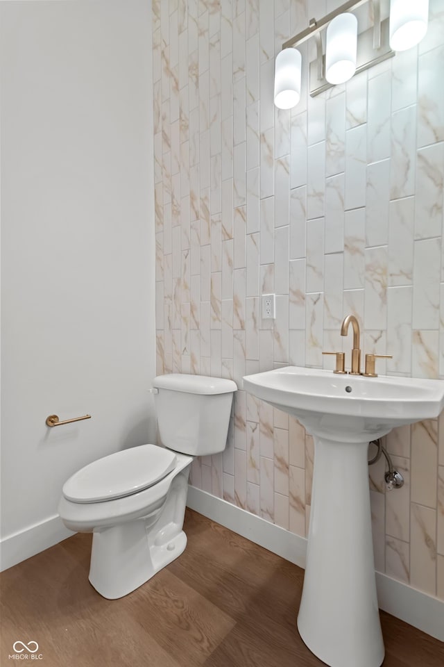 bathroom with toilet, wood finished floors, and baseboards