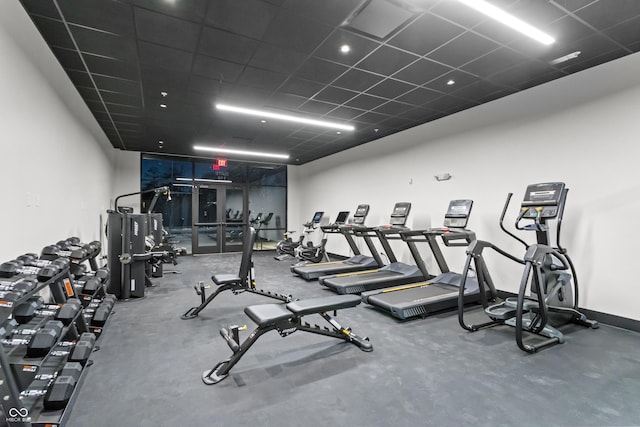 gym with a drop ceiling and baseboards