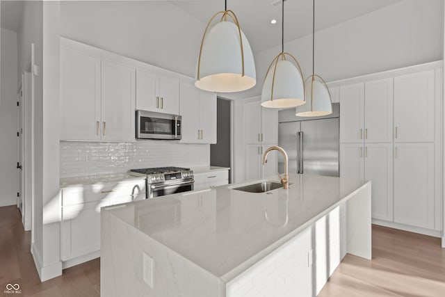 kitchen featuring white cabinets, stainless steel appliances, light wood-style floors, and a sink