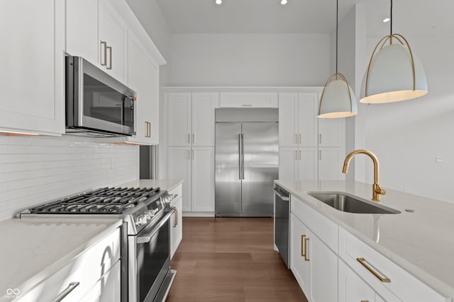 kitchen featuring light stone countertops, a sink, stainless steel appliances, white cabinets, and backsplash