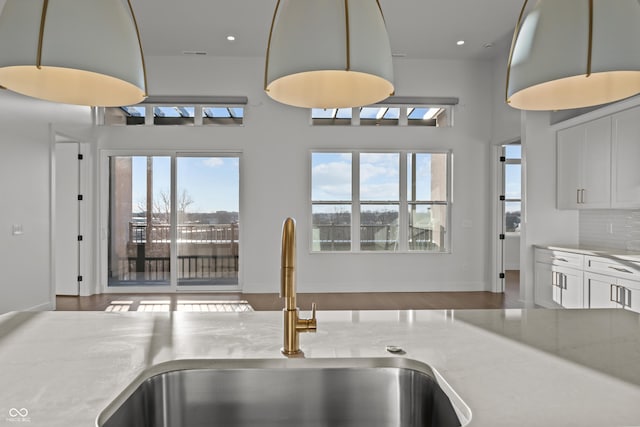 kitchen featuring a wealth of natural light, decorative backsplash, visible vents, and a sink