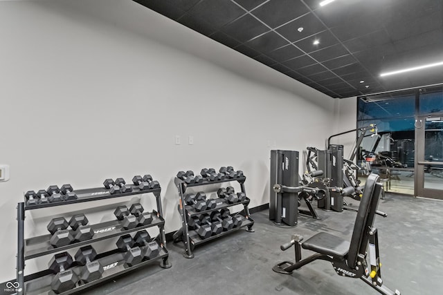 workout area with a paneled ceiling and baseboards