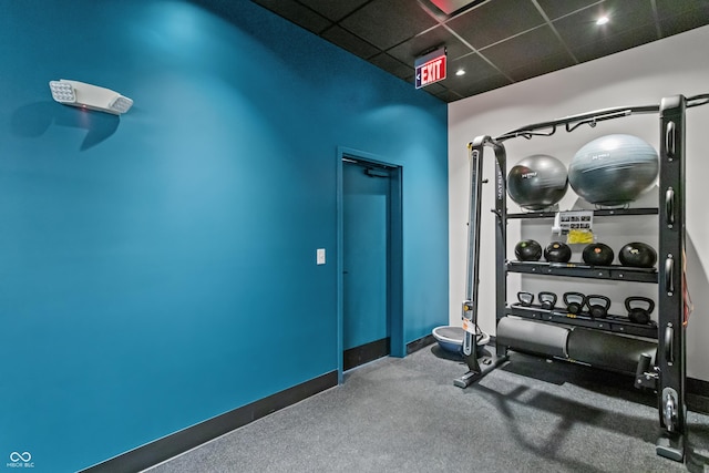 exercise room featuring carpet, a paneled ceiling, and baseboards