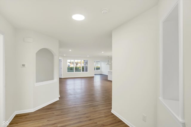 corridor with hardwood / wood-style floors and a notable chandelier