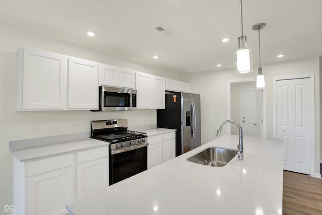 kitchen with stainless steel appliances, white cabinetry, sink, decorative light fixtures, and dark hardwood / wood-style flooring