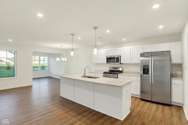 kitchen featuring light hardwood / wood-style floors, a center island with sink, appliances with stainless steel finishes, decorative light fixtures, and white cabinets