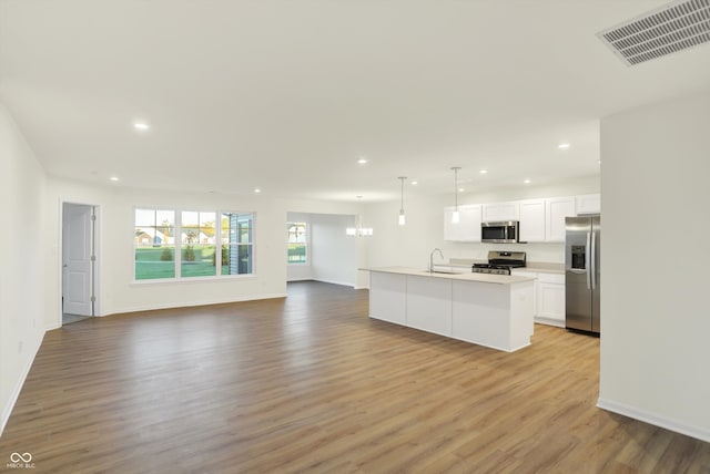 kitchen with white cabinetry, an island with sink, light hardwood / wood-style floors, and stainless steel appliances