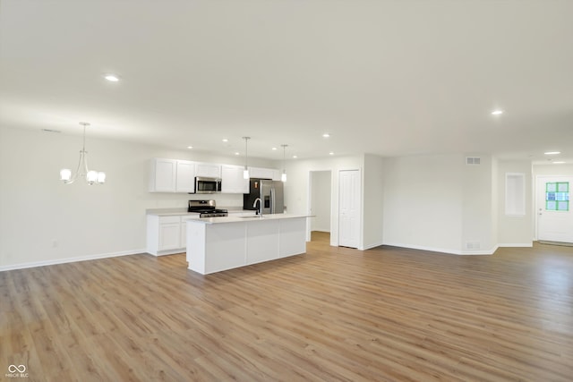 kitchen featuring stainless steel appliances, white cabinets, pendant lighting, and light hardwood / wood-style flooring