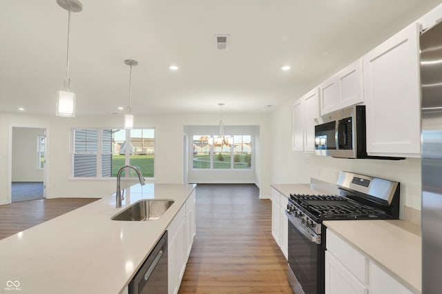 kitchen with dark hardwood / wood-style flooring, sink, white cabinetry, appliances with stainless steel finishes, and decorative light fixtures