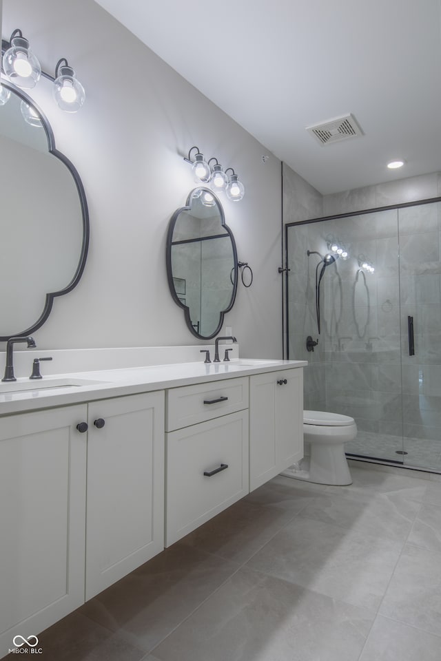 bathroom with toilet, dual bowl vanity, tile patterned flooring, and a shower with shower door