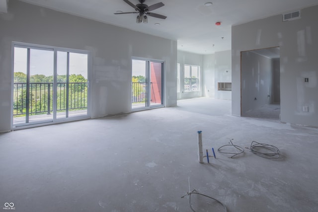 unfurnished living room with ceiling fan and concrete floors