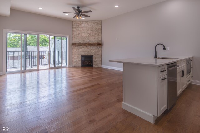 kitchen with sink, ceiling fan, hardwood / wood-style floors, and a fireplace