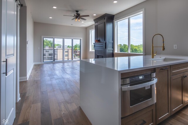 kitchen featuring ceiling fan, stainless steel oven, sink, and dark hardwood / wood-style floors