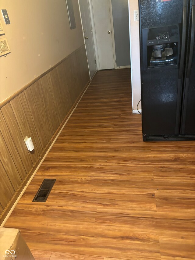 hallway with wood walls, electric panel, and wood-type flooring