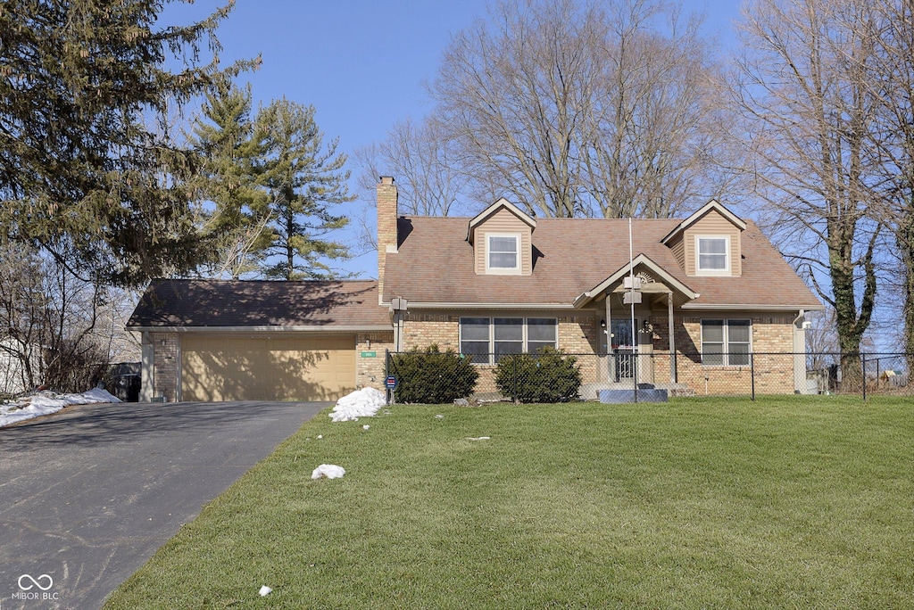 cape cod house featuring a garage and a front lawn