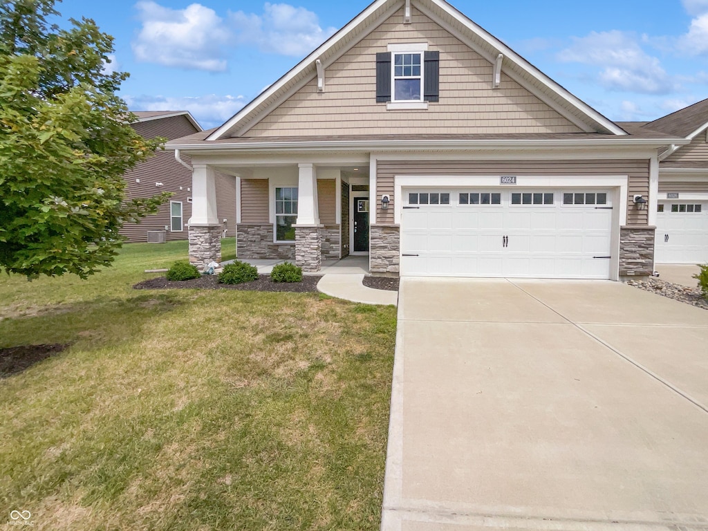 view of front of house with driveway, stone siding, covered porch, and a front yard