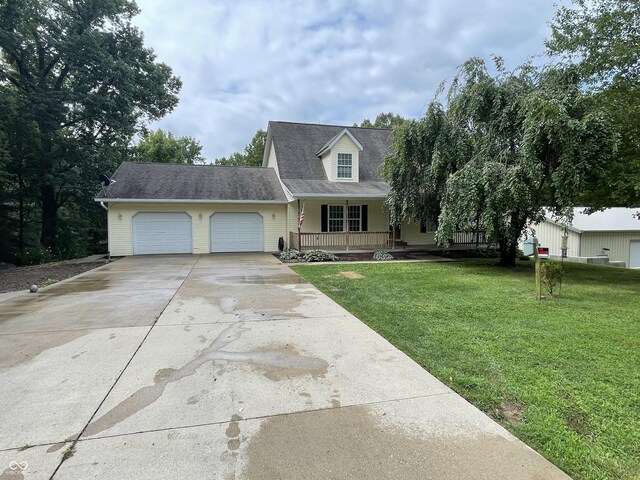 view of front of home featuring covered porch, a garage, and a front lawn