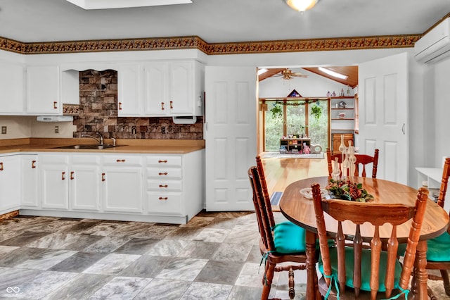 kitchen featuring a wall mounted air conditioner, backsplash, ceiling fan, sink, and white cabinetry