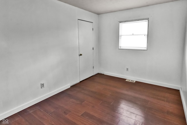 spare room featuring baseboards, wood finished floors, and visible vents