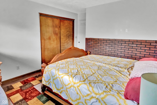 bedroom with a closet, brick wall, and hardwood / wood-style flooring