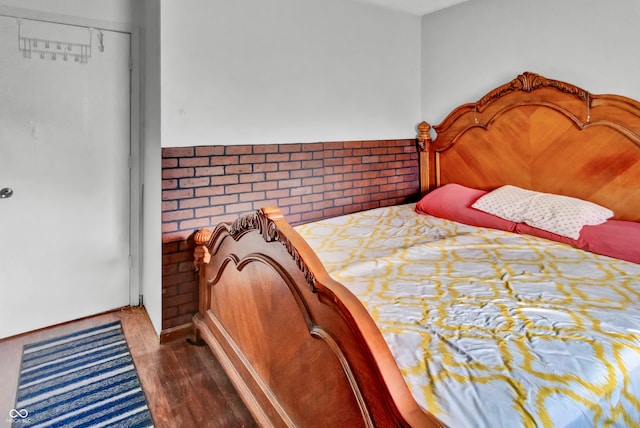 bedroom featuring dark wood-type flooring, brick wall, and a closet