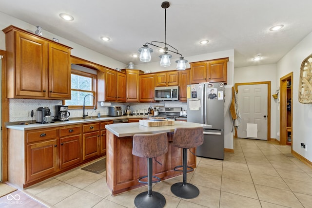 kitchen with a center island, stainless steel appliances, sink, hanging light fixtures, and light tile patterned flooring