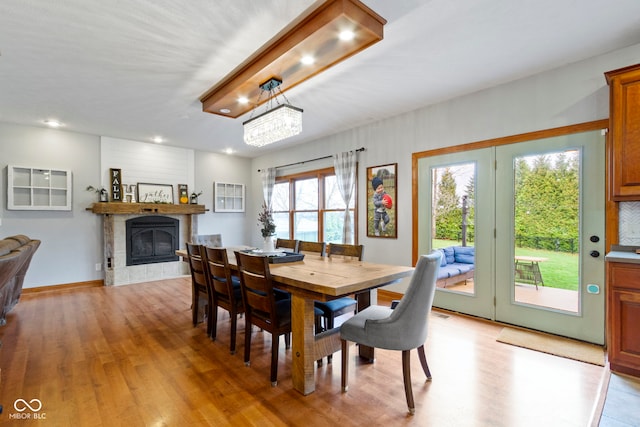 dining space featuring a tiled fireplace, a chandelier, and light hardwood / wood-style floors