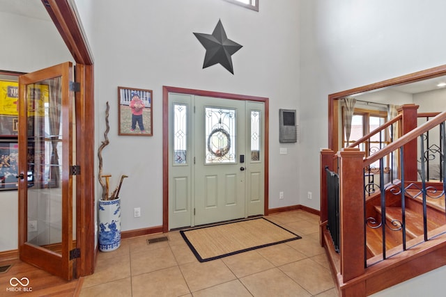 foyer featuring light tile patterned floors, a healthy amount of sunlight, and a high ceiling