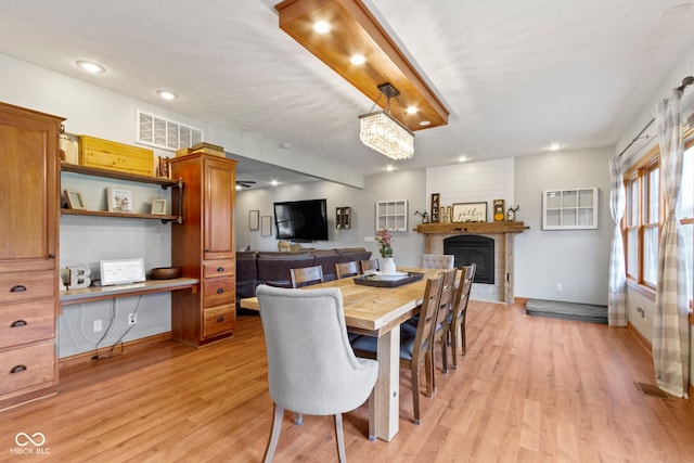 dining area featuring light wood-type flooring and a fireplace