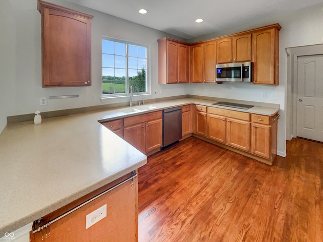 kitchen with sink, kitchen peninsula, dark hardwood / wood-style floors, and stainless steel appliances