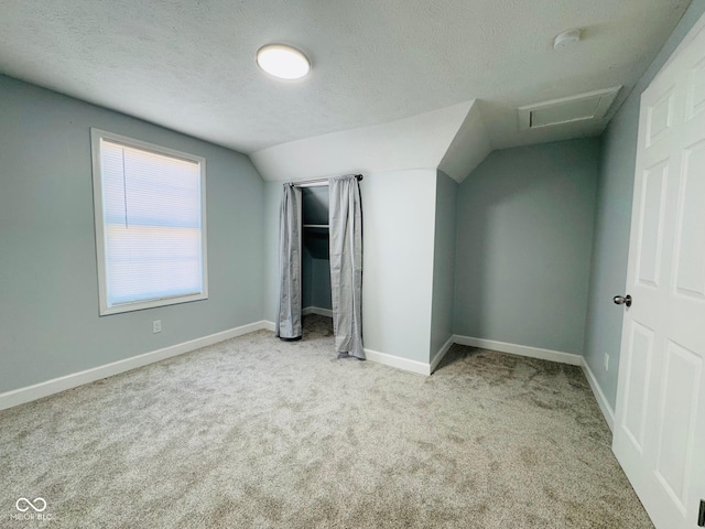 unfurnished bedroom with lofted ceiling, light colored carpet, and a textured ceiling