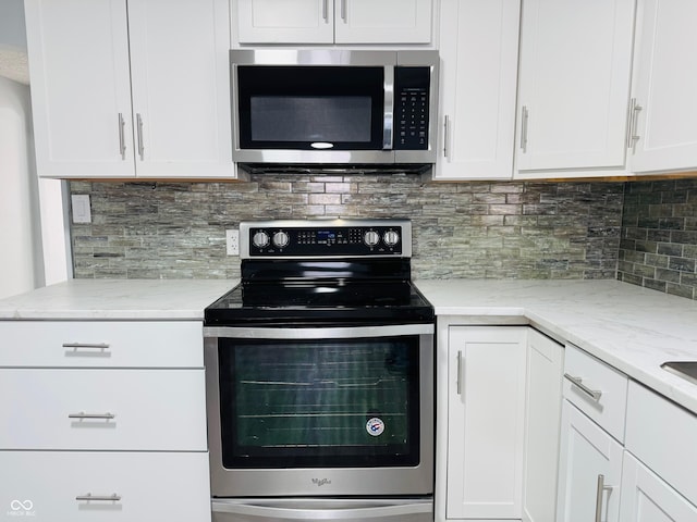 kitchen with backsplash, light stone countertops, white cabinets, and appliances with stainless steel finishes