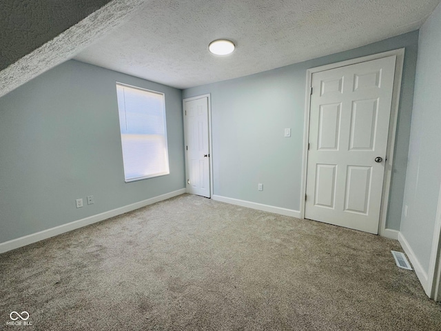 interior space with vaulted ceiling, carpet, and a textured ceiling