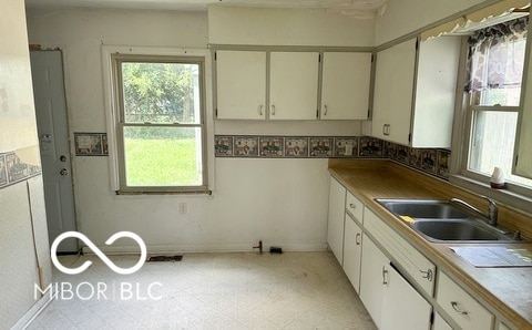 kitchen featuring sink, white cabinetry, and light tile patterned floors